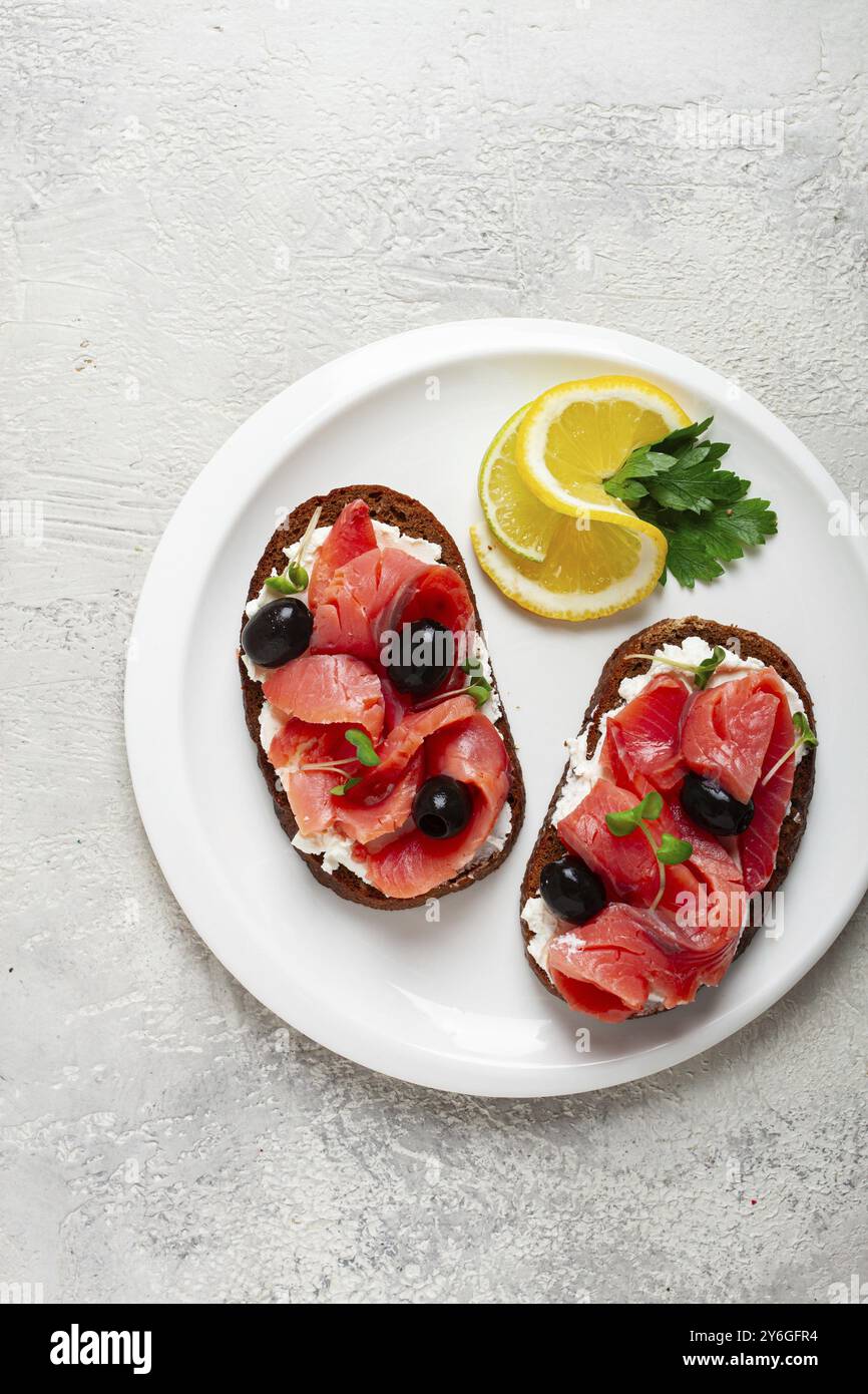 Lebensmittelfotografie, Sandwiches mit Frischkäse, Kicherlachs, kalt geräuchert, Getreidebrot, Draufsicht, Frühstück, Zitrone und Petersilie, keine Leute Stockfoto