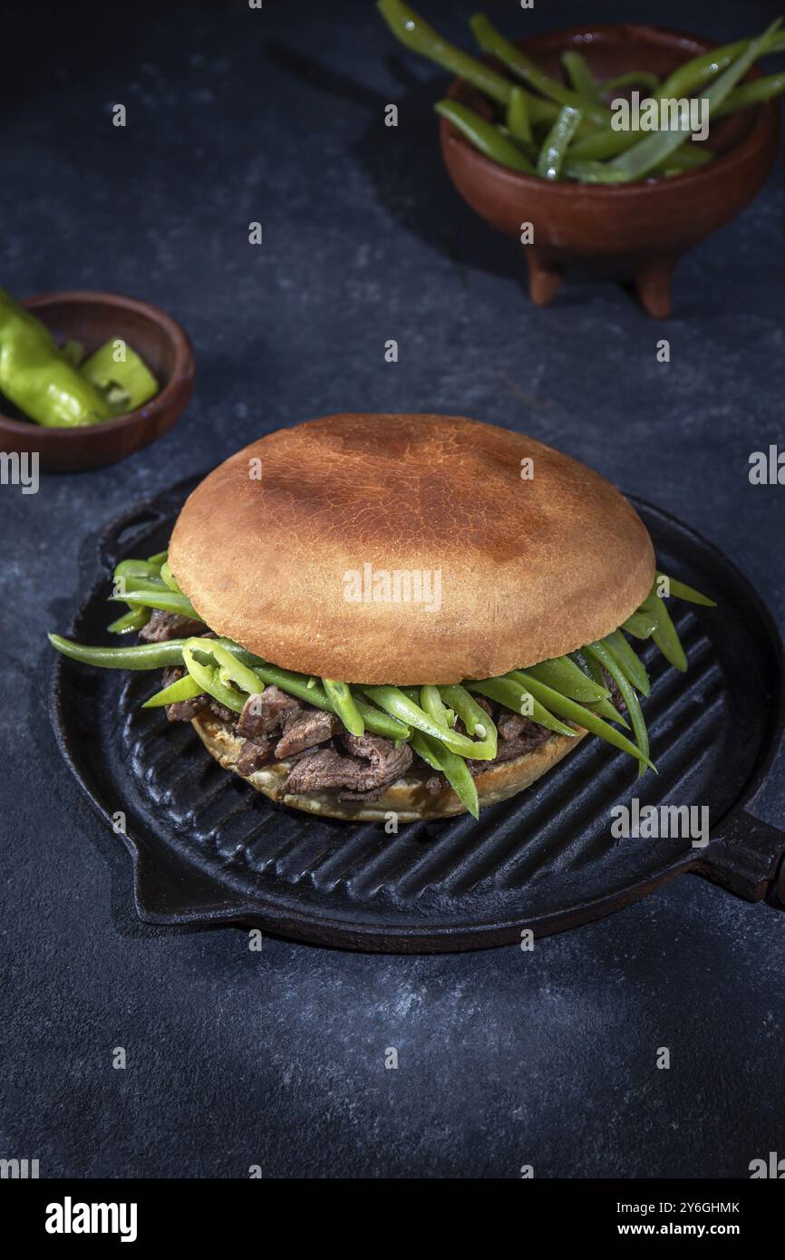 Essen, Essen, chilenischer lateinamerikanischer Sandwich-Burger Chacarero mit erstklassigen Rindfleischscheiben und grüner Bohne auf schwarzem Hintergrund Stockfoto