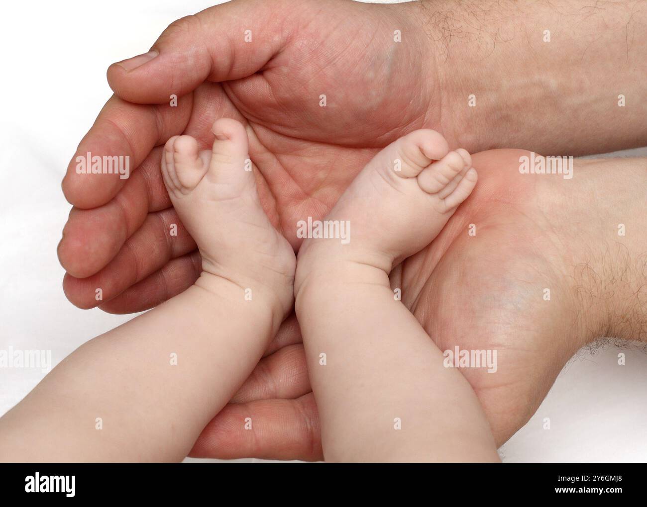 Vater hält Babyfüße auf den Handflächen Stockfoto