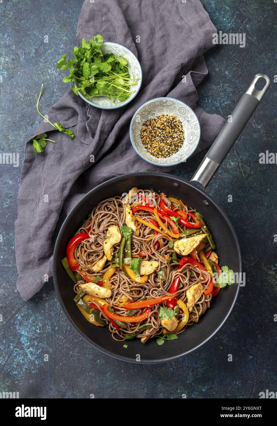 Essen, Essen, japanisches Gericht Buchweizen-Soba-Nudeln mit Huhn und Gemüse Karotten, Paprika und grünen Bohnen im Wok auf dunkelblauem Hintergrund Stockfoto