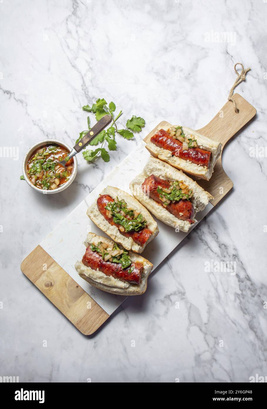 Essen, chilenische und argentinische Küche. Traditionelles Choripan mit würzigem Pebre, Chorizo-Sandwich mit Chorizo-Würstchen und Brot Stockfoto