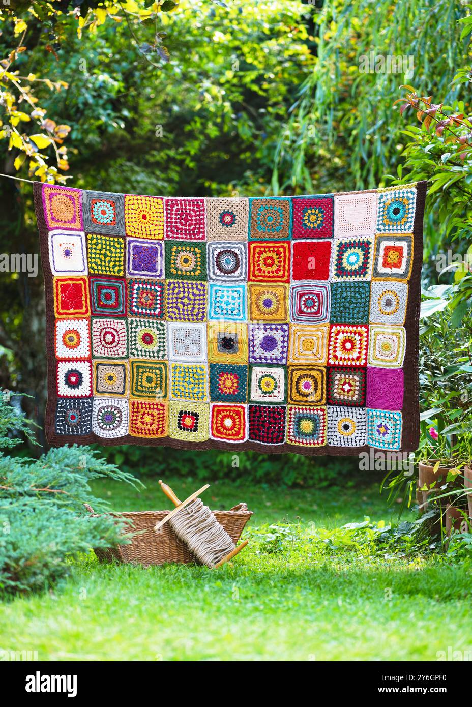 Handgemachte Vintage-Häkelei Oma Quadrat hängt an der Schnur im Sommer-Cottage-Garten. Stricken im Stil eines Flickenteppichs. Hobby-Konzept. Stockfoto