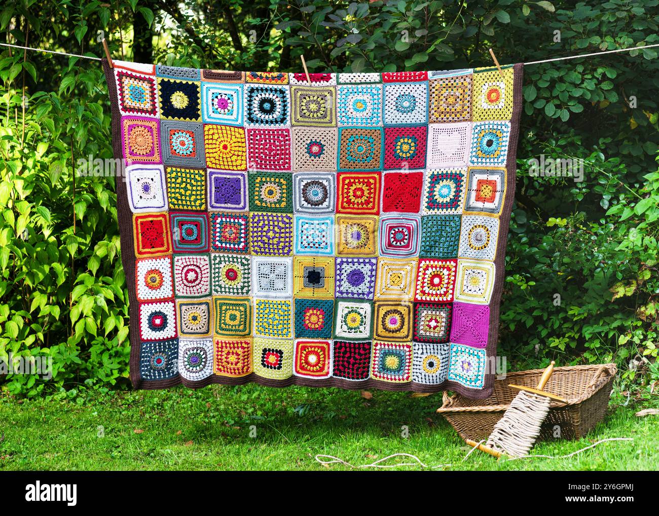 Handgefertigtes farbenfrohes Vintage-Oma-Quadrat, das draußen an der Schnur hängt. Stricken im Stil eines Flickenteppichs. Hobby-Konzept. Kopierbereich. Stockfoto