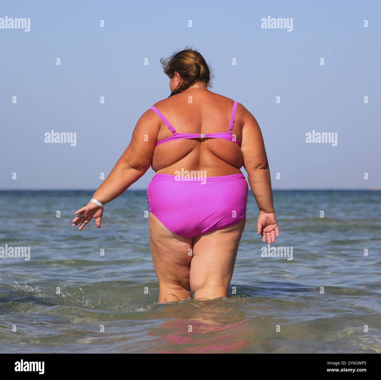 Übergewichtige Frau badet im Meer, Blick von hinten Stockfoto