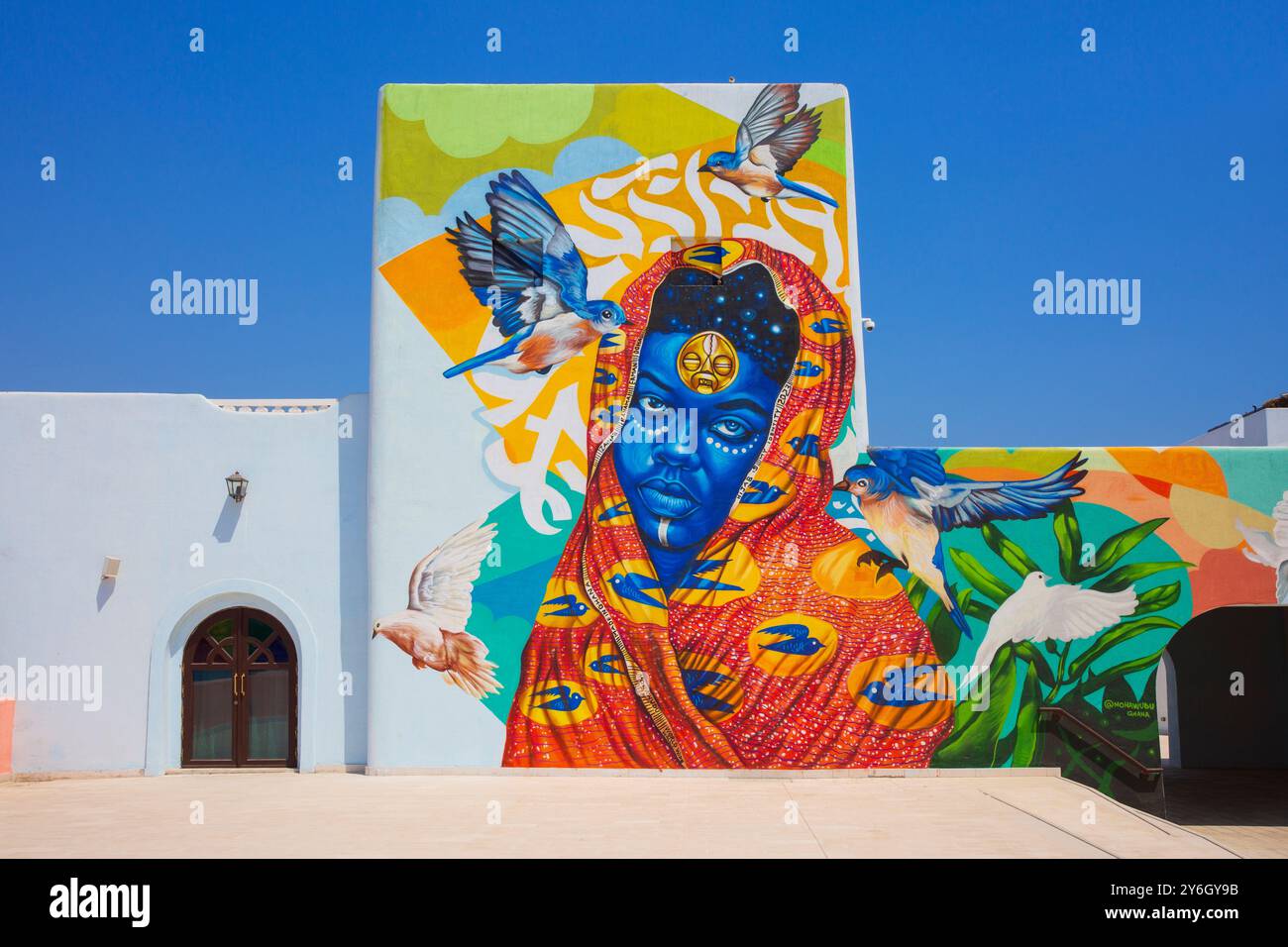 Ein wunderschönes Wandgemälde einer Dame mit einem Kopftuch von Mohawudu (Ghana) im Mina District in Doha, Katar Stockfoto