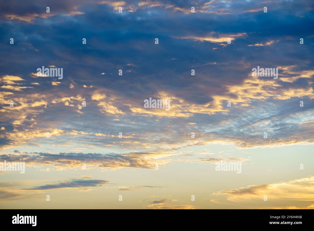 Goldenes Sonnenlicht bricht durch Schichten dunkler und heller Wolken in einem riesigen Himmel. Stockfoto