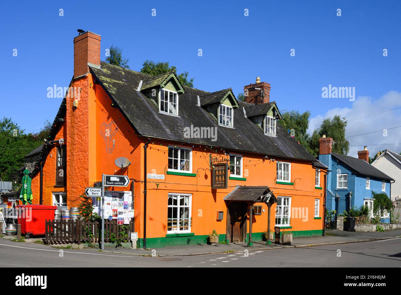 Bischops Castle, England, Großbritannien - 11. September 2024; farbenfroher orange Six Bells Pub in Bishops Castle mit benachbartem blauem Haus Stockfoto