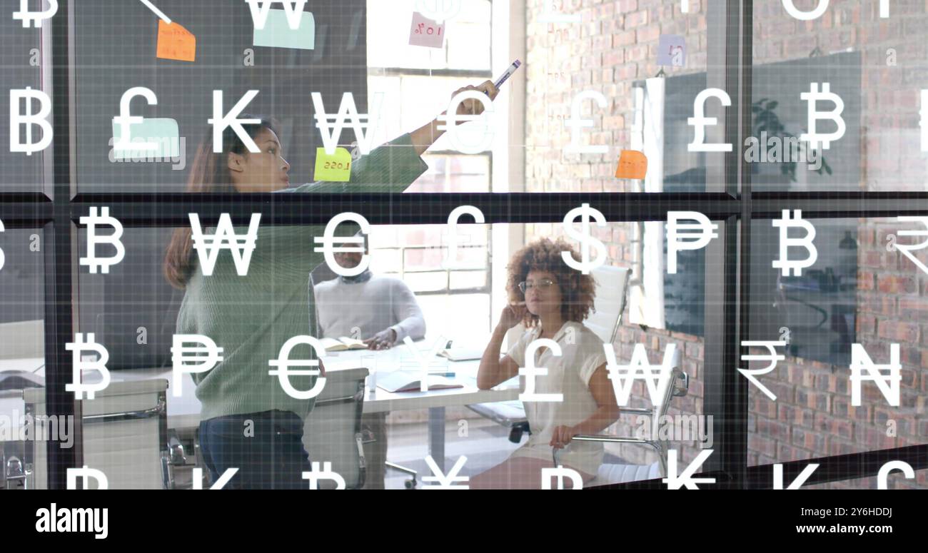 Bild von Währungssymbolen über verschiedenen Geschäftsleuten, die über die Arbeit im Büro sprechen Stockfoto