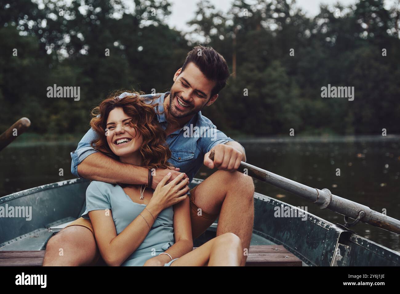 Von allem wegkommen. Wunderschönes junges Paar, das sich umschließt und wegblickt, während es ein romantisches Date auf dem See genießt Stockfoto