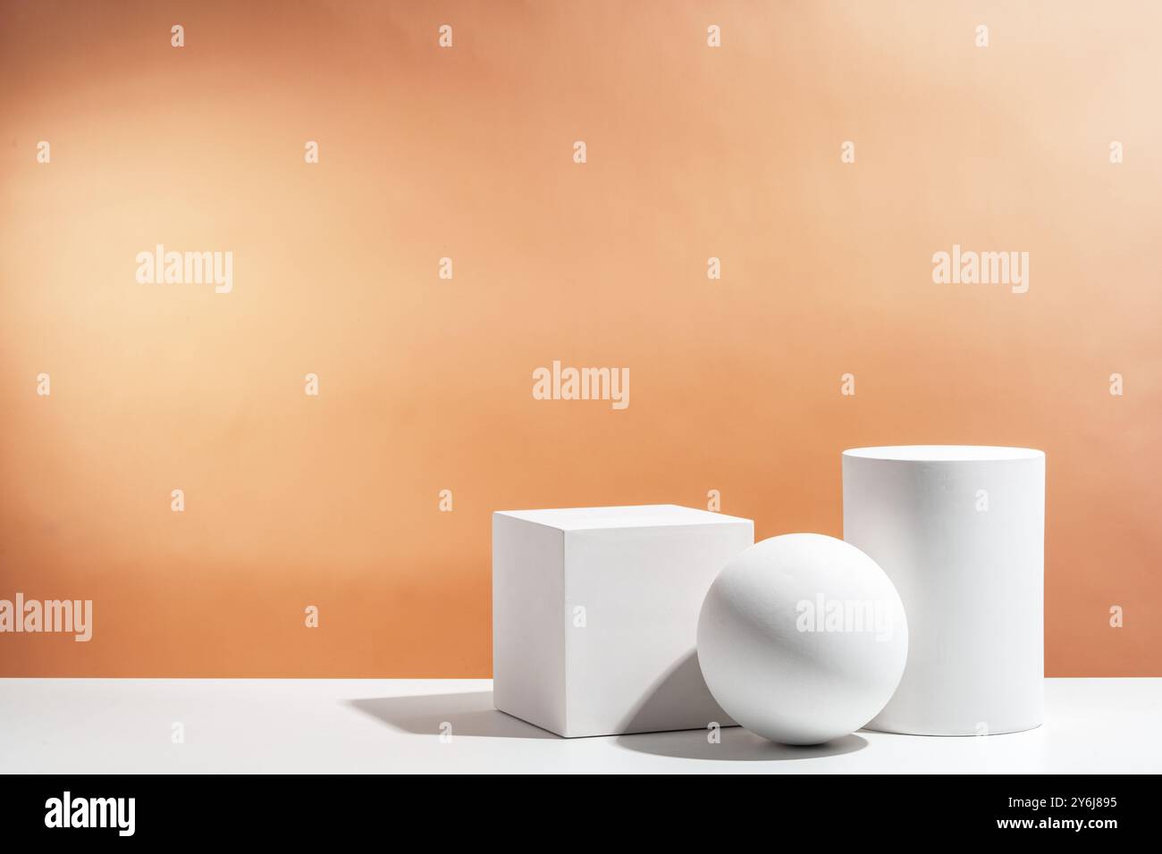 Weiße geometrische Formen, die stilvoll auf einem weichen pfirsichfarbenen Hintergrund in einer minimalistischen Umgebung angeordnet sind Stockfoto