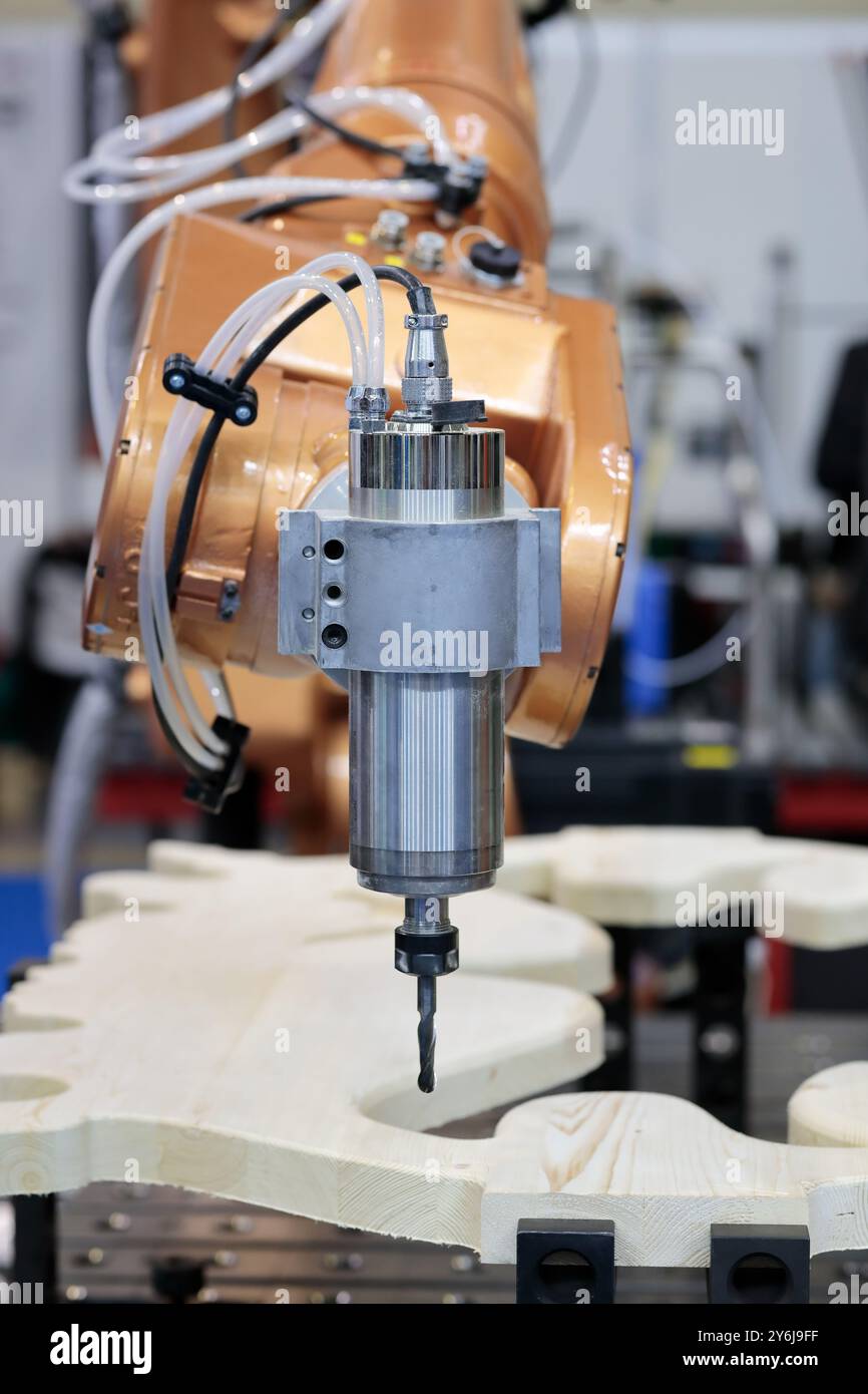 Roboterarm mit Fräsende-Endeffektor bearbeitet eine Holzplatte. Roboterzelle fräsen. Sechs-Achsen-Roboter mit Schneidwerkzeugen können Schneiden, Bohren, Stockfoto