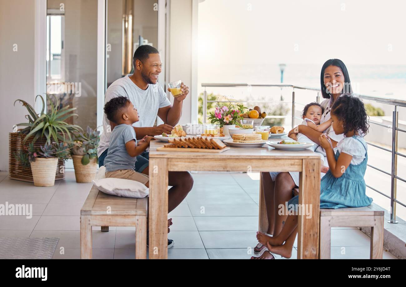 Mom, Dad und Kinder am Tisch zum Frühstück mit einem Lächeln, Essen und am Morgen zusammen auf dem Balkon. Mutter, Vater und Kinder mit Essen, Liebe und Stockfoto