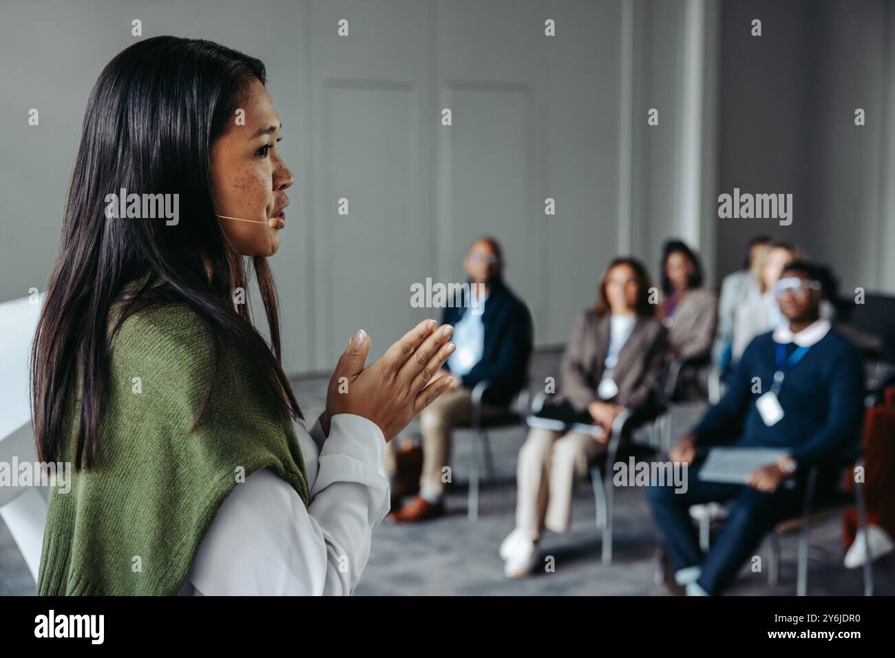 Eine Sprecherin hält ein ansprechendes Seminar für ein aufmerksames Publikum in einer professionellen Umgebung, in dem Selbstvertrauen und Kommunikationsfähigkeiten hervorgehoben werden. Stockfoto