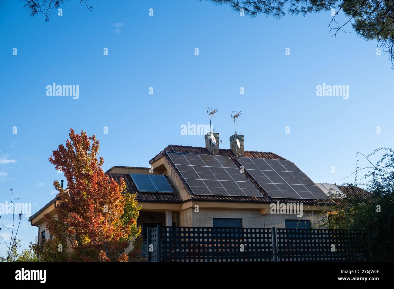 Ein riesiges, individuelles Chalet-Haus mit Schornsteinen und Photovoltaik-Solarpaneelen für alternative und nachhaltige Energie auf dem Dach. Es ist Herbst und es Stockfoto