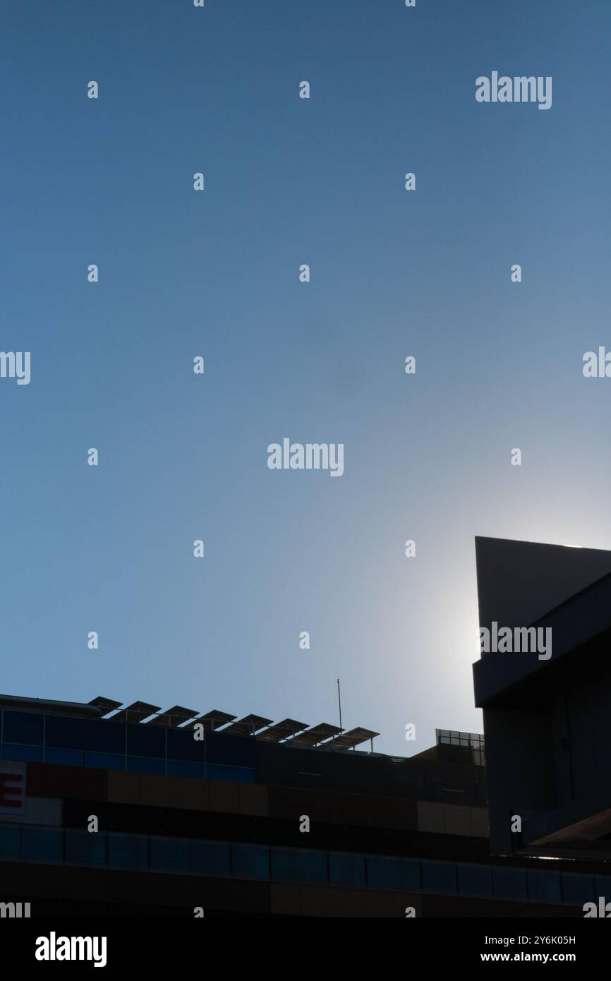 Hintergrundbeleuchtete Ansicht des Daches eines modernen Bürogebäudes mit einer Photovoltaik-Solarpaneel-Installation auf dem Gemeinschaftsdach. Konzept einer Umwelt Stockfoto