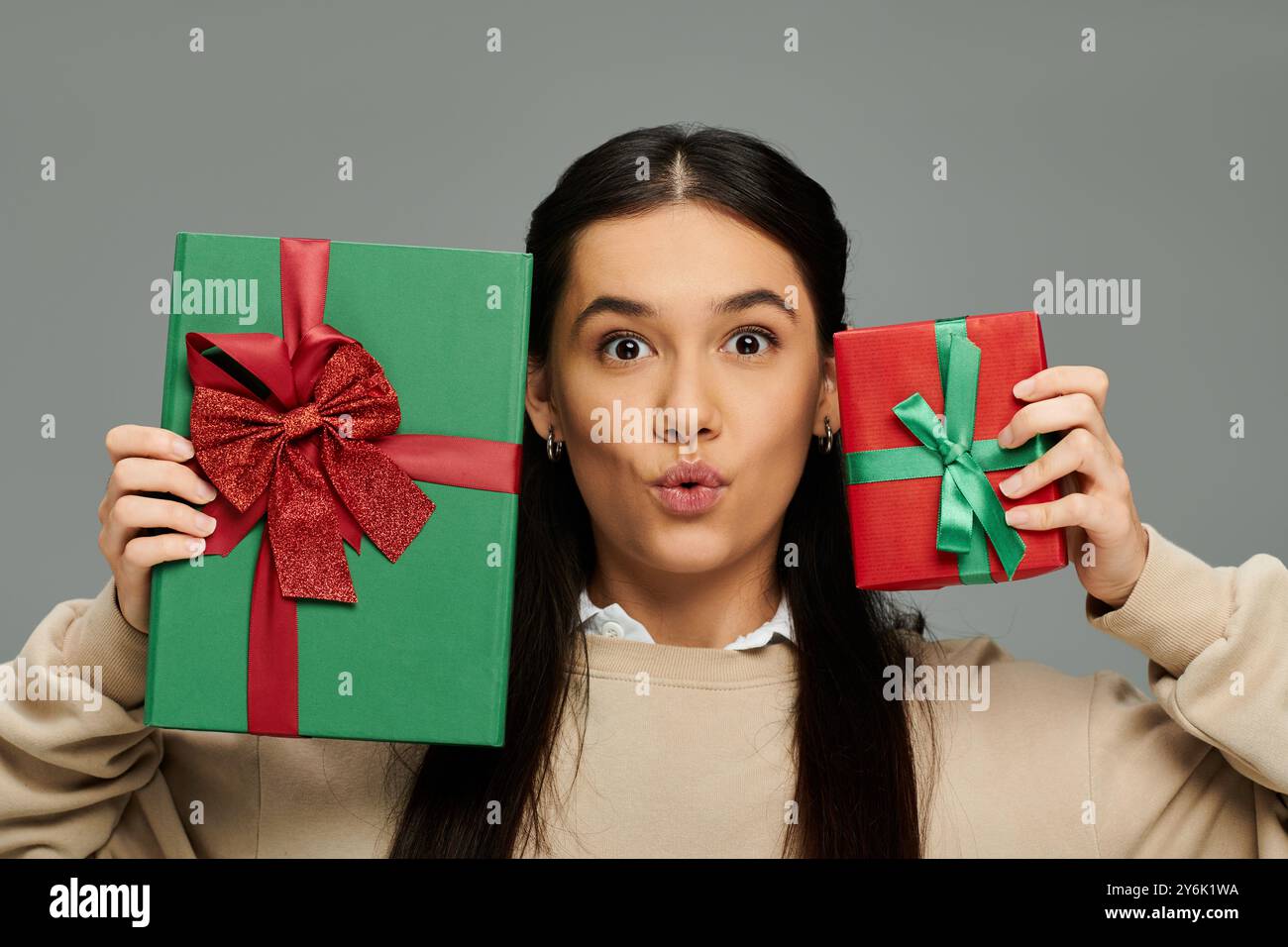 Eine junge Frau bringt Freude zum Ausdruck, während sie zwei wunderschön gewickelte Geschenke hält, die Freude zum Ausdruck bringen. Stockfoto