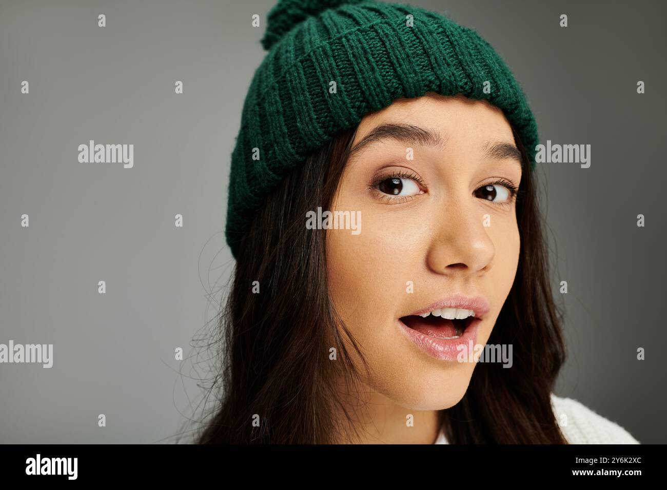 Eine modische junge Frau mit einer grünen Mütze zeigt einen verspielten, emotionalen Ausdruck. Stockfoto