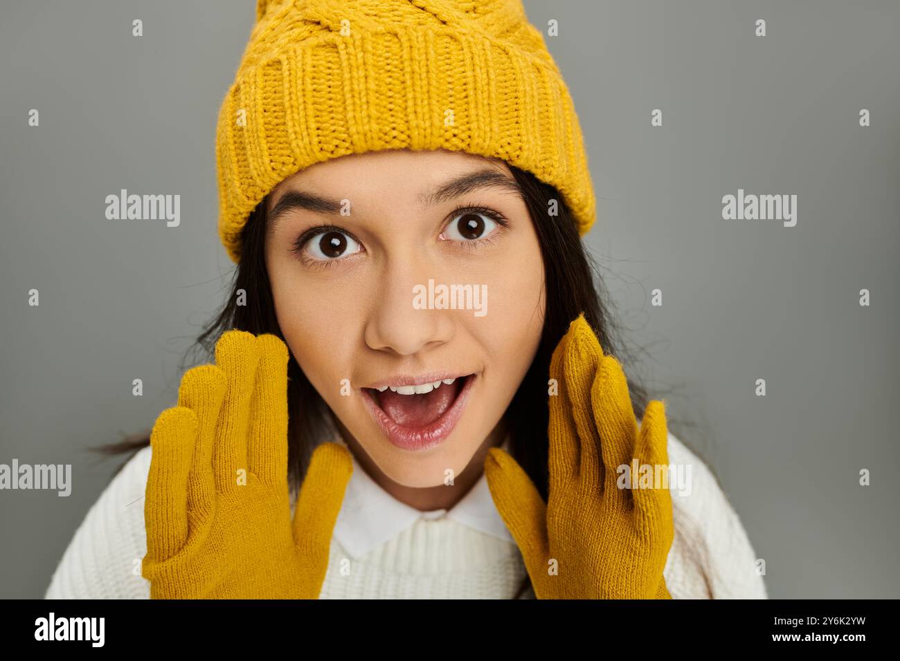 Eine fröhliche und stilvolle Frau in Winterkleidung teilt ihre freudige Überraschung mit lebendigen Handschuhen. Stockfoto