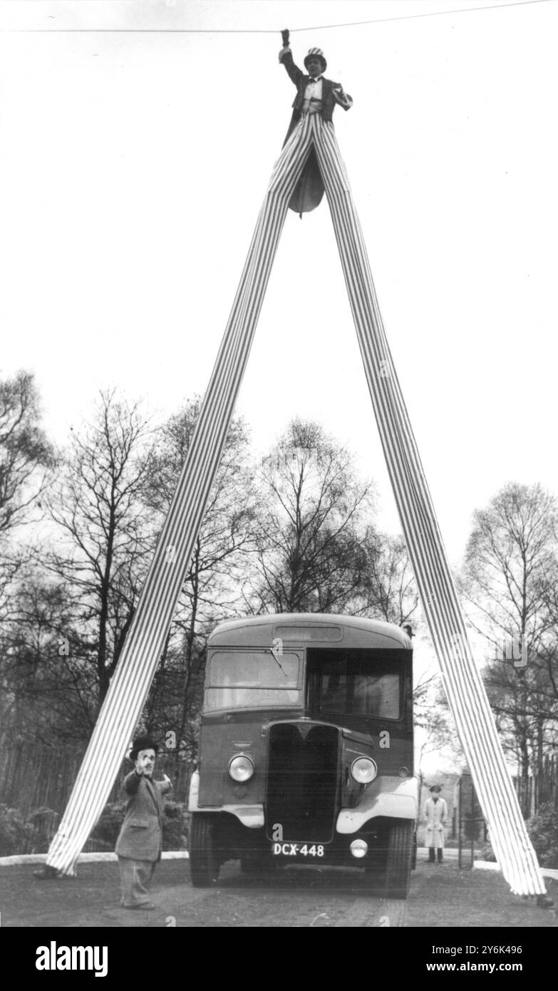 Zwischen den Beinen des Stelzkünstlers Henry Lewandowski fährt ein Reisebus während der Proben des Bertram Mills Circus in Ascot für die kommende Saison im Olympia zu Weihnachten . Henrys Stelzen sind 34 Meter hoch am 1. Dezember 1955 Stockfoto