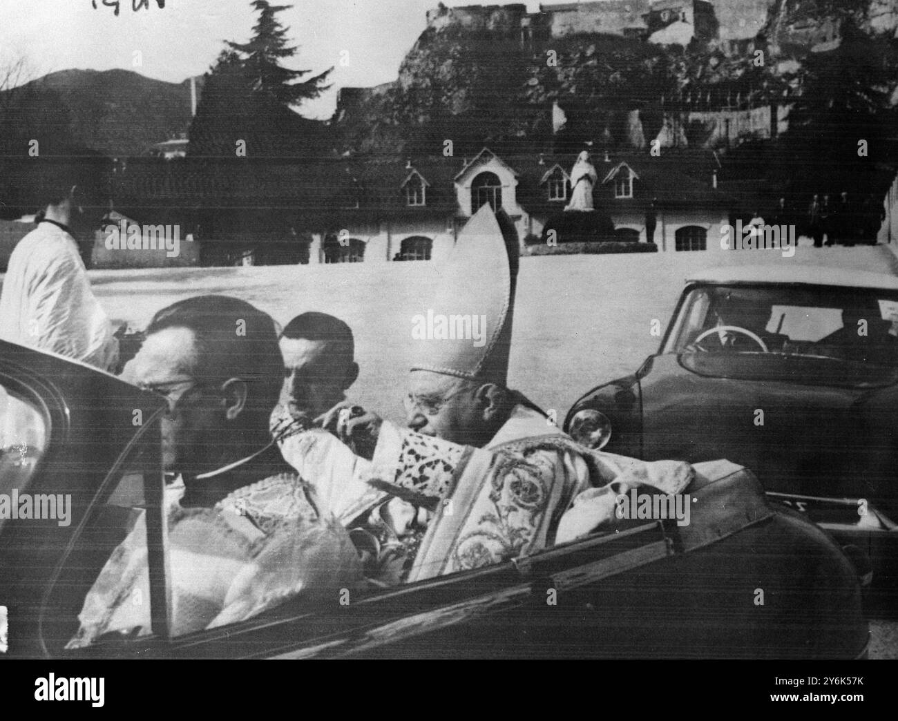 Der päpstliche Vertreter kommt zu den Jubiläumsfeiern in Lourdes . Kardinal besichtigte das Äußere der Basilika in einem offenen Auto die Statue der Heiligen Bernadette ist im Hintergrund am 24. März 1958 zu sehen Stockfoto