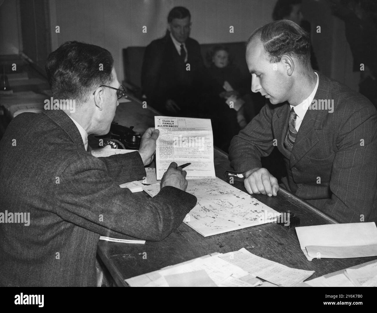 Der Vater der Guten Quads verlangt Familienzuschüsse für seine 5 Kinder. Der Beamte der örtlichen Niederlassung der nationalen Versicherung zeigt Herrn Good, wie er das Formular ausfüllt. Juni 1948 Stockfoto