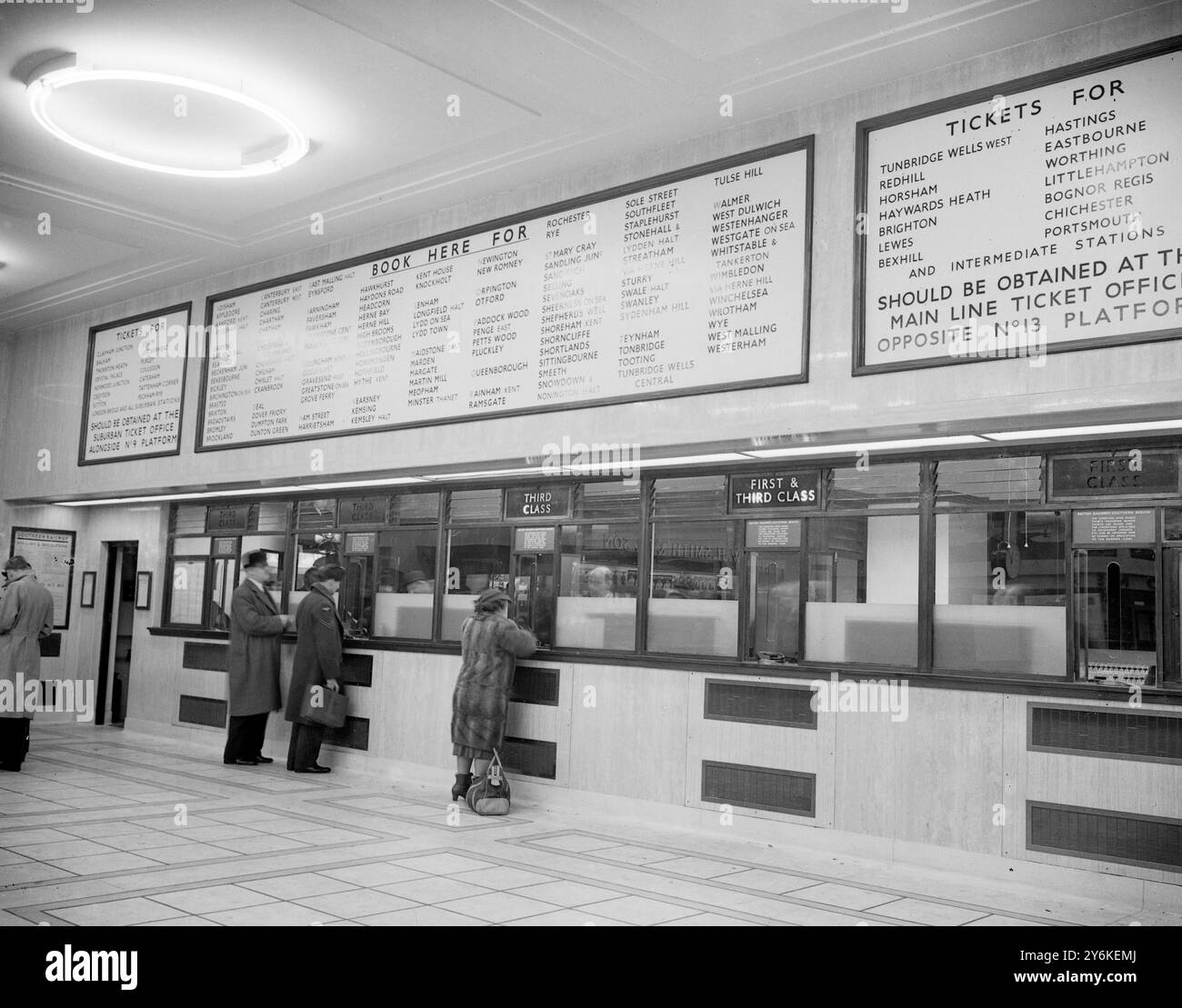 Ein Blick auf die wiederaufgebaute Eastern Section Booking Hall an der Victoria Station in London, mit dem Ticketschalter mit Glasfront und Passagieren, die Tickets kaufen. Zentral beheizt und beleuchtet mit Leuchtstofflampen, in mittleren weiß- und Goldtönen, um eine warme und komfortable Atmosphäre zu schaffen, verfügt es über einen Bücherstand, Telefone und einen Fahrplanstand. - 5. Februar 1951. ©TopFoto Stockfoto