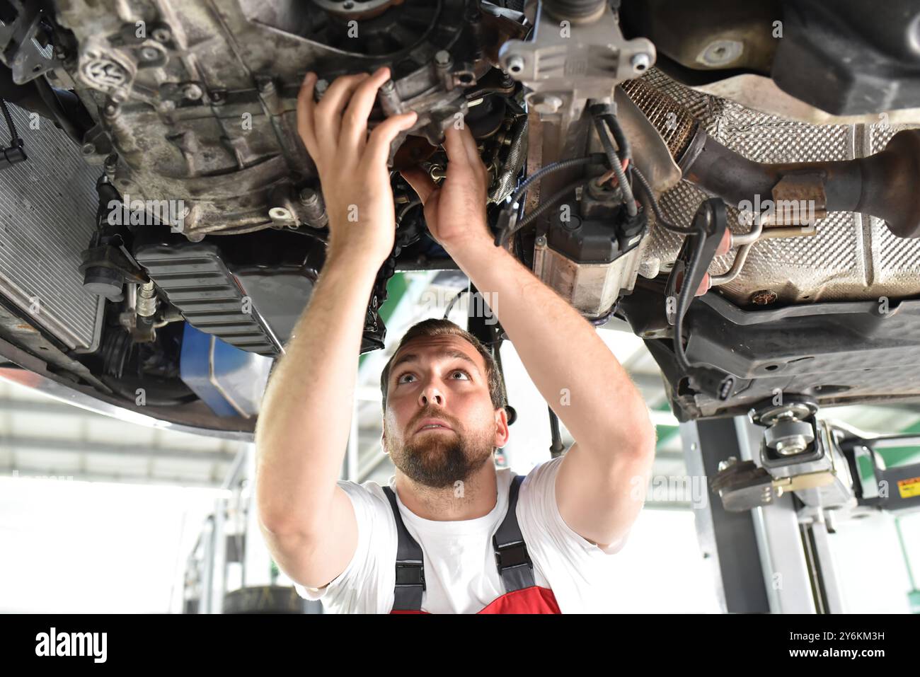 Automechaniker in Arbeitskleidung arbeitet in einer Werkstatt und repariert ein Fahrzeug Stockfoto