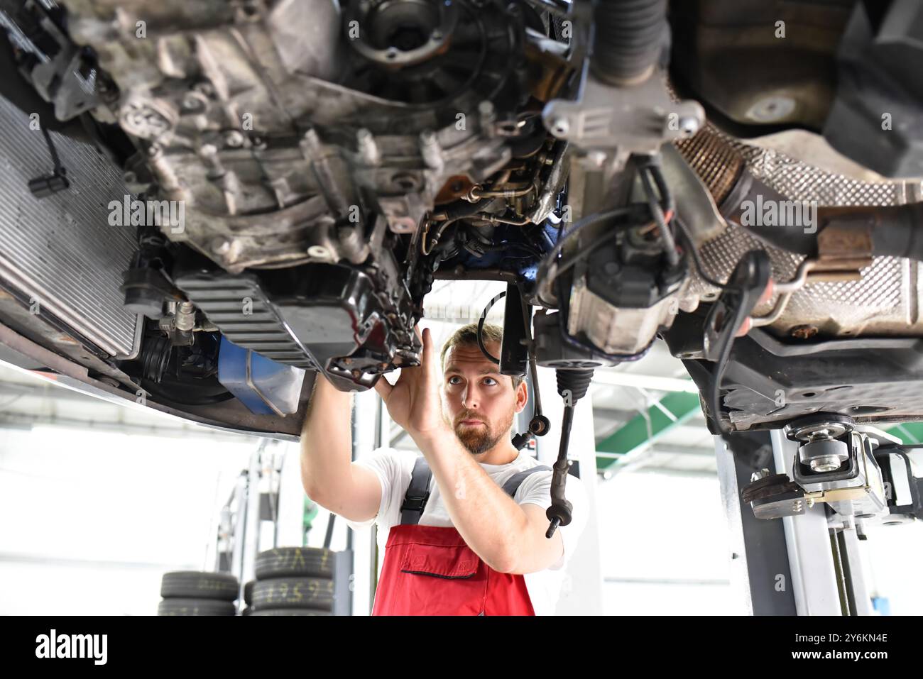 Automechaniker in Arbeitskleidung arbeitet in einer Werkstatt und repariert ein Fahrzeug Stockfoto