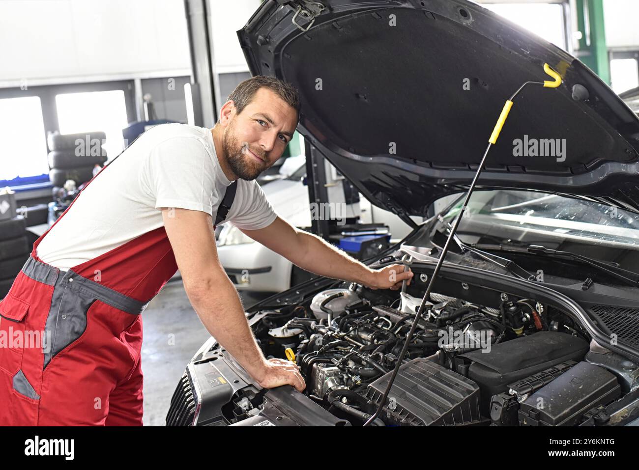 Automechaniker in Arbeitskleidung arbeitet in einer Werkstatt und repariert ein Fahrzeug Stockfoto