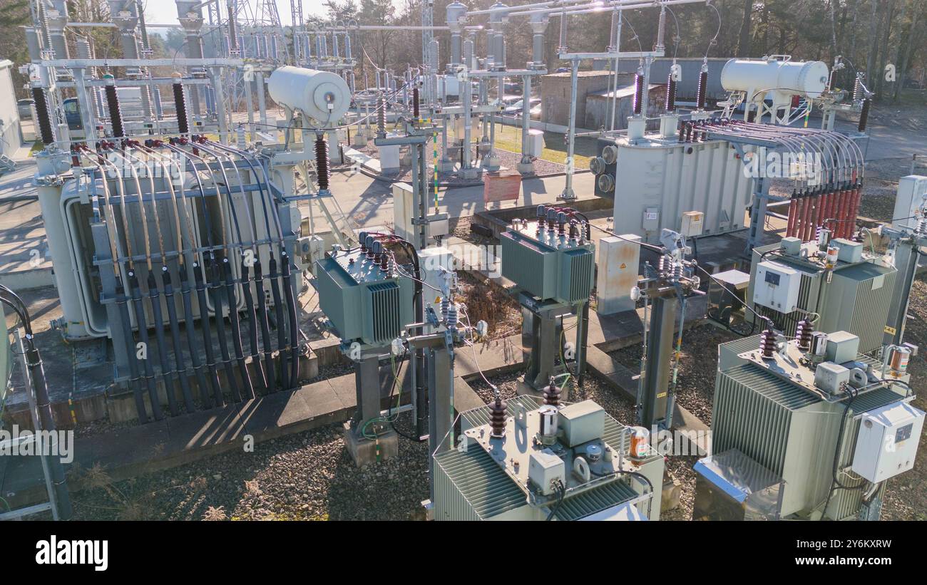 Eine industrielle elektrische Unterstation mit verschiedenen Transformatoren, Leistungsschaltern und Stromleitungen. Die Szene spielt draußen mit klarem Himmel und Stockfoto