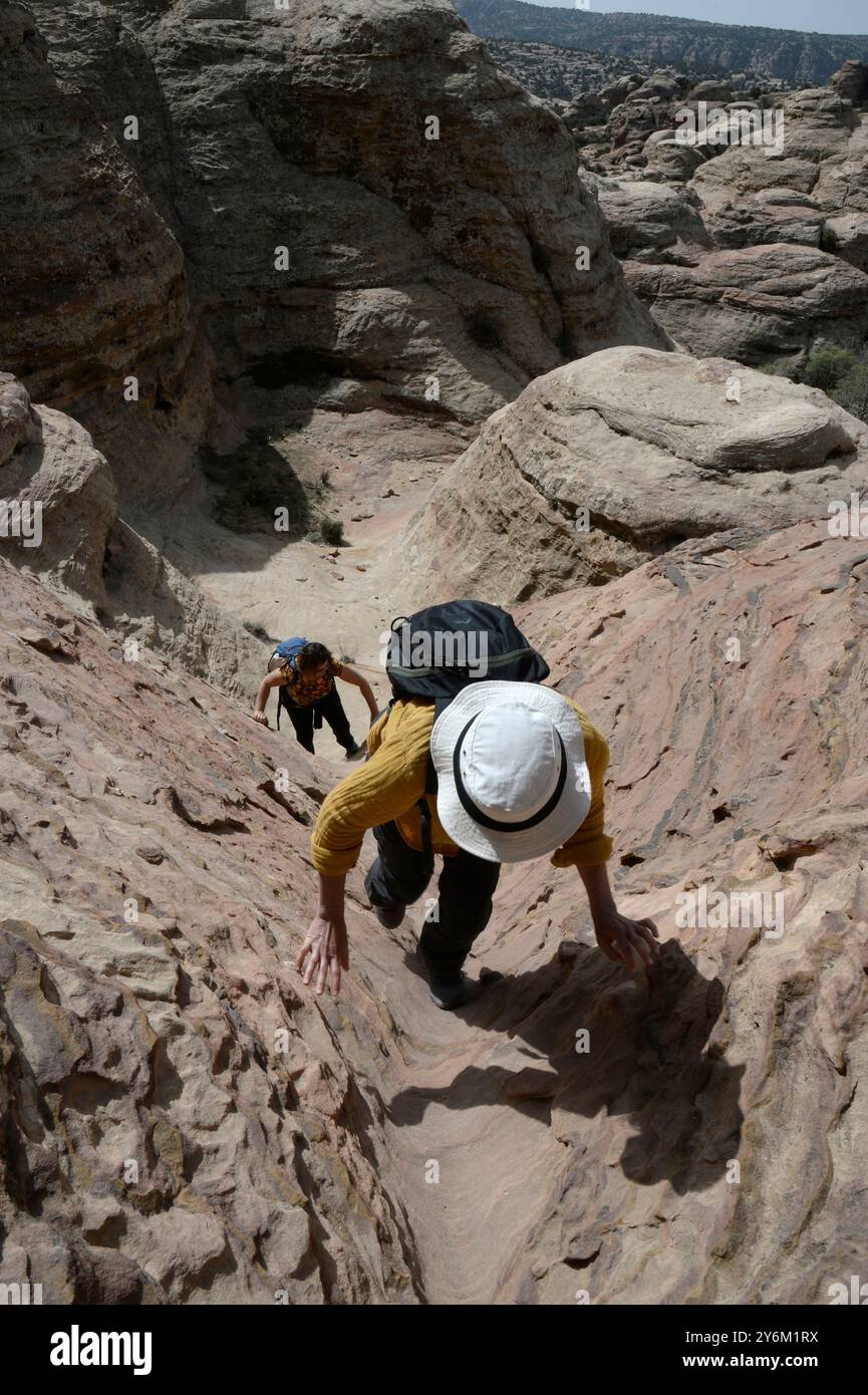 Jordanien, Naher Osten, Dana Naturschutzgebiet, zwei junge Frauen wandern in einem schmalen Sandsteinkamin hinauf Stockfoto