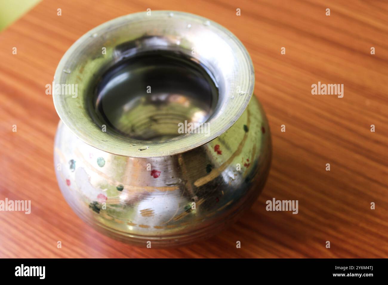 Messingstahlgefäß „Kalash“ (Lota), ein traditioneller kugelförmiger Wasserbehälter, der auf einem braunen hölzernen Hintergrund steht und seine Kultur und seinen Nutzen hervorhebt Stockfoto