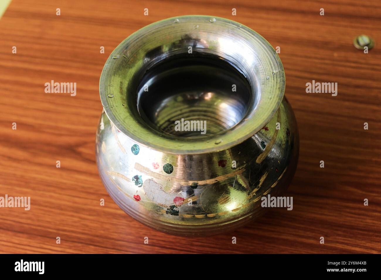 Messingstahlgefäß „Kalash“ (Lota), ein traditioneller kugelförmiger Wasserbehälter, der auf einem braunen hölzernen Hintergrund steht und seine Kultur und seinen Nutzen hervorhebt Stockfoto