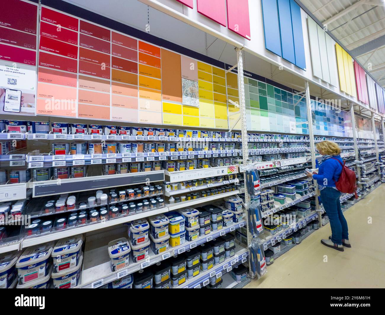 Blonde Frau in der Farbabteilung eines großen Baumärkels Stockfoto
