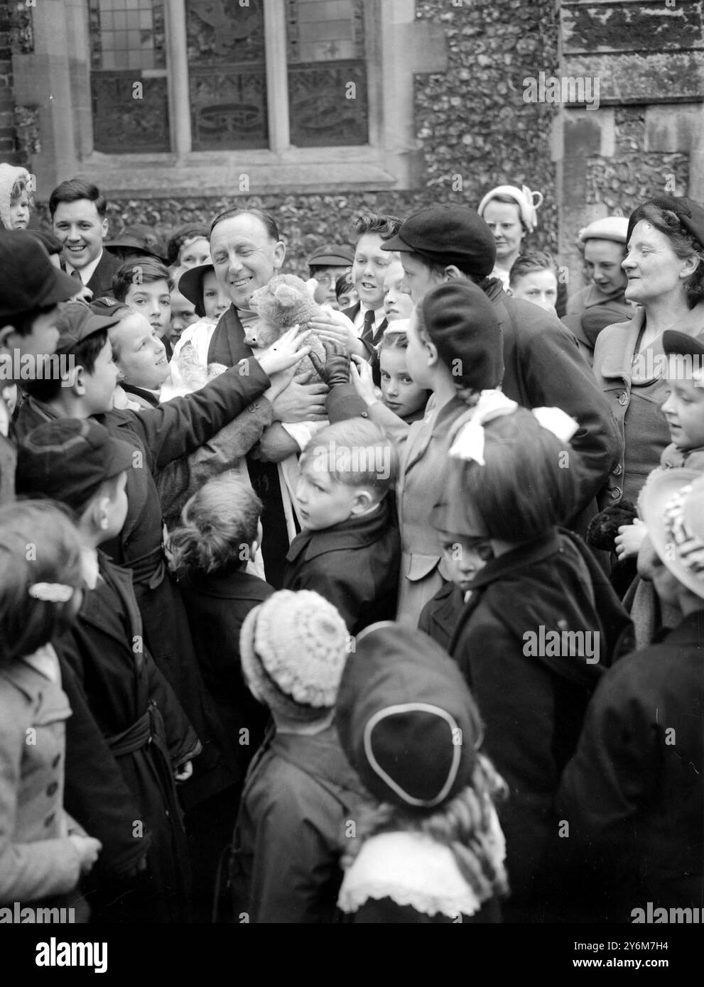 Bromley, Kent der Pfarrer John Rahe Hughes, Vikar der St. Mary's Church, Bromley, steht an seiner Kirchentür, um Kinder willkommen zu heißen, die Lämmer zu einem besonderen Kindergottesdienst bringen. Sechs Lämmer, die nur zwei oder drei Wochen alt waren, wurden von einer Farm in Kent geliehen, um das Thema des besonderen Gottesdienstes zu illustrieren: "Der gute Hirte - die Lämmer mussten innerhalb von zwei Stunden bei ihren Müttern sein. - 5. April 1953 Stockfoto