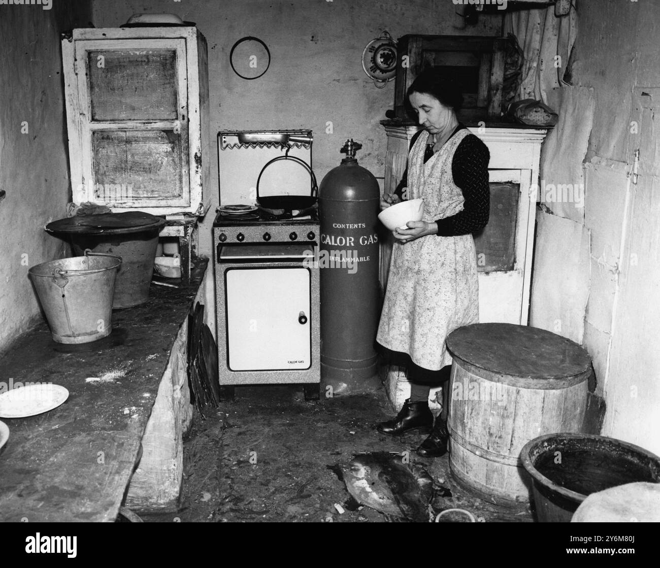 Mrs. Peters ging 1916 mit ihrem Mann auf die Farm. Jetzt ist sie Witwe, 59, sieht aber viel jünger aus. Mit Hilfe ihrer beiden Brüder schafft sie es sehr geschickt. Das ist ihre Küche - der einzige moderne Komfort ist das Flaschengas und der Herd - der ungefähr 13 Meilen gebracht wird, wenn eine neue Flasche benötigt wird. 1950 Stockfoto