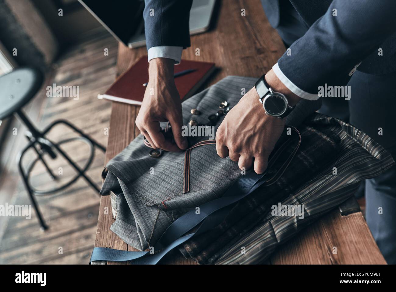 Ein weiterer geschäftiger Tag. Nahaufnahme des Modedesigners, der während seiner Arbeit im Modestudio Knöpfe auswählt Stockfoto