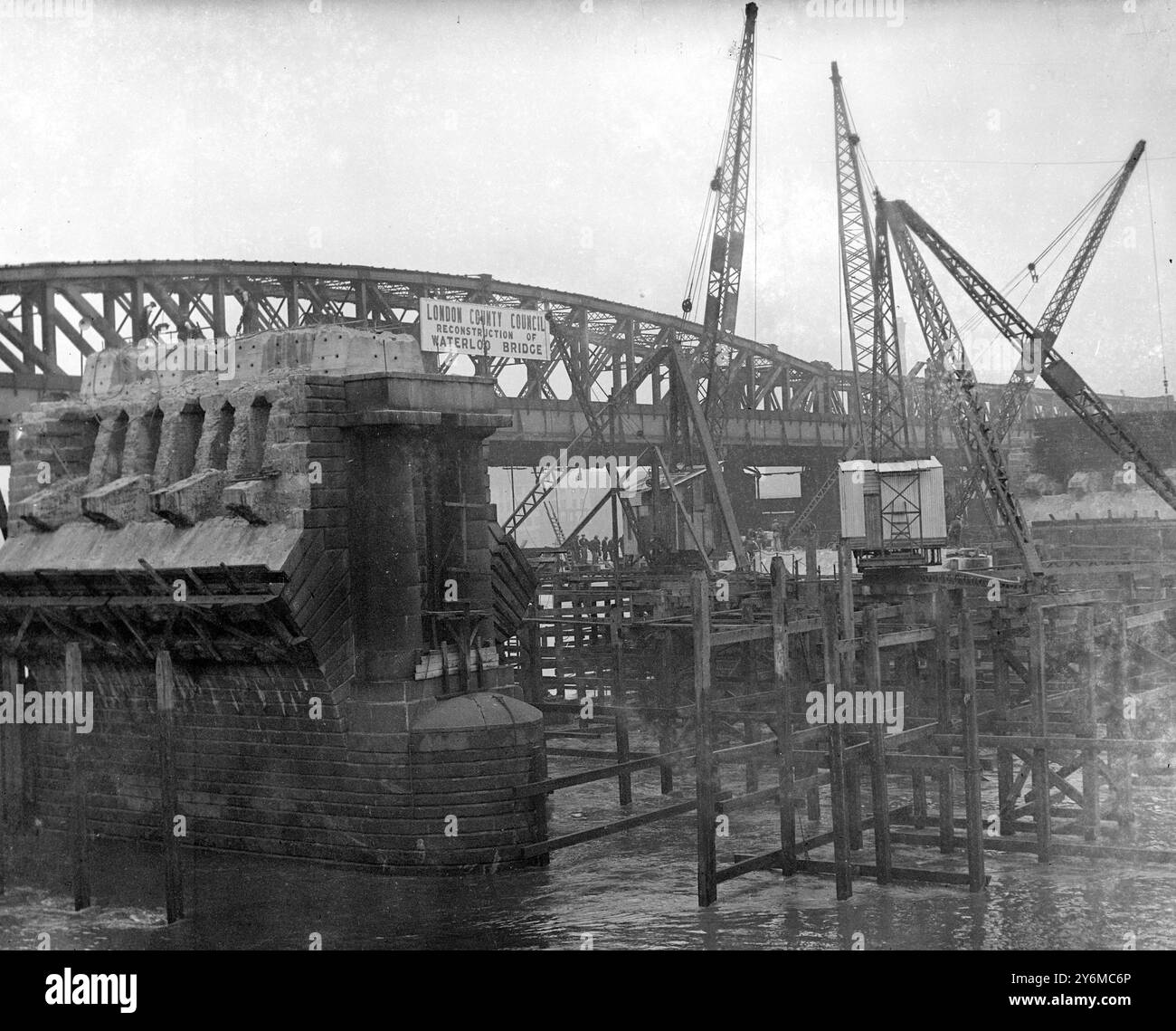 Vor einigen Jahren gab der London County Council nach vielen Diskussionen Anweisungen für den Abriss der Water loo Bridge, eine technische Meisterleistung, die Londoner mit unfehlbarem Interesse verfolgt haben. Jetzt haben sie auf beiden Seiten der temporären Brücke eine Nachricht angebracht, die Passanten das Offensichtliche mitteilt, dass die Waterloo Bridge rekonstruiert wird. 17. September 1936 Stockfoto