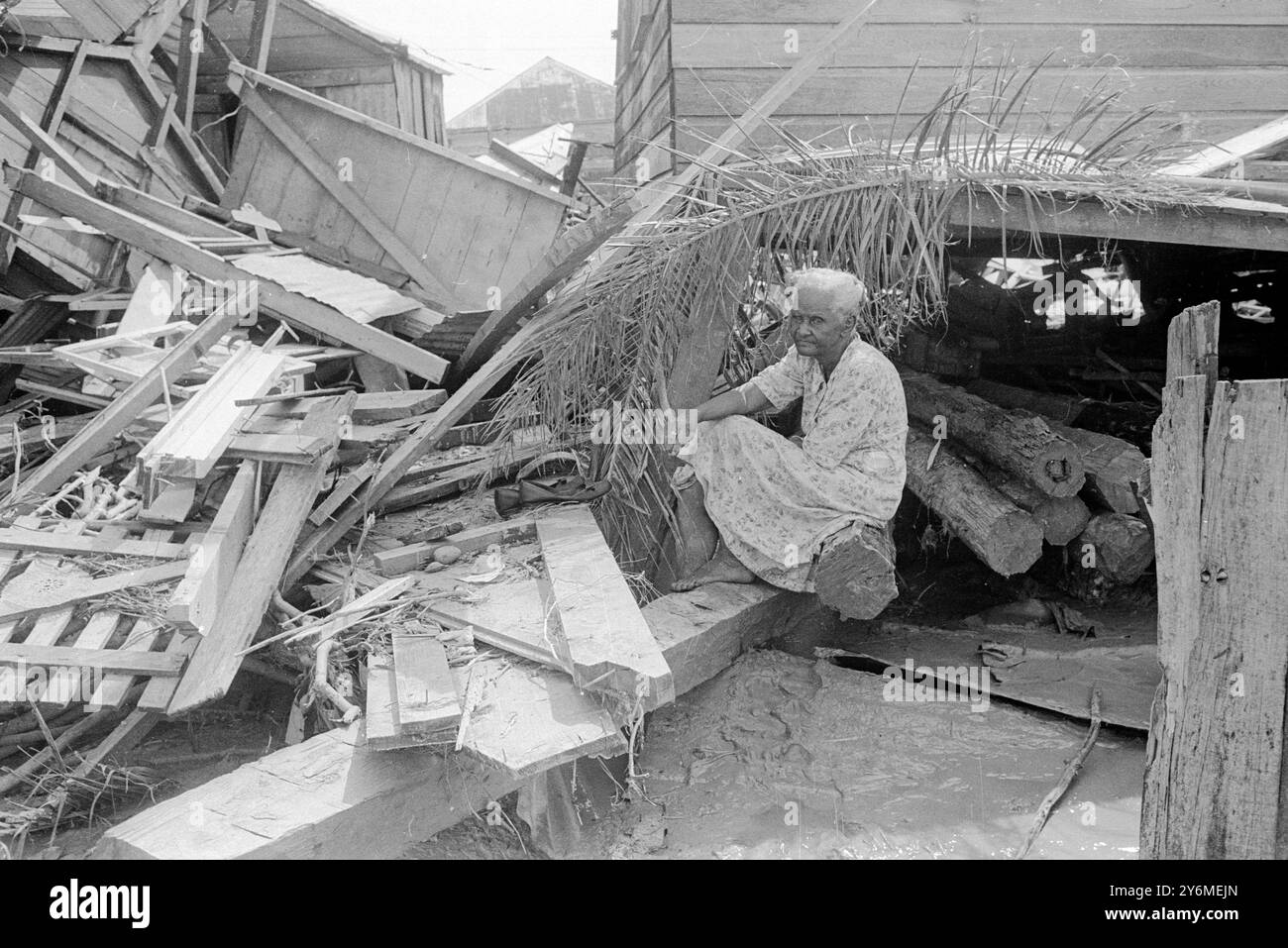 Belize, Britisch-Honduras: Während Rettungskräfte die zerstörten Ruinen von Belize, der Hauptstadt von Britisch-Honduras, durchsuchen, wurden die Füße eines Jungen getötet, als Hurrikan Hattie am 31. Oktober die Stadt traf. Ragt unter der Plane des Opfers hervor. Mehr als 100 Menschen wurden getötet und Tausende wurden obdachlos. Dem Mann links wurde sein Hemd am 3. November 1961 praktisch vom Rücken gerissen Stockfoto