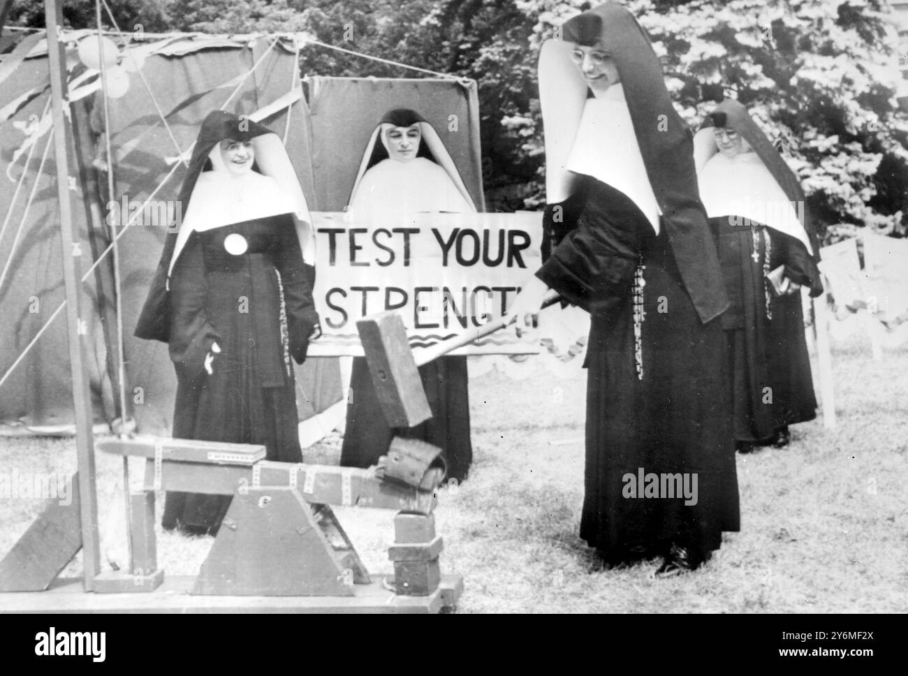 Dousman, Wisconsin: Sie versucht, die Glocke zu läuten, aber nicht in der Hoffnung, eine Zigarre zu bekommen, ist Schwester Sybilla während eines Picknicks für Nonnen im St. Monica-Seminar in der Nähe. Nonnen nahmen an einer Vielzahl von Spielen Teil, darunter Softball, Tennis Hufeisen Pitching und Angeln während des Tages. Ebenfalls im Bild sind Schwester Reginald links und Schwester Pius hinter dem Schild. Alle sind Schulschwestern von Notre Dame, Oconomowoc, Wisconsin. August 1959 Stockfoto