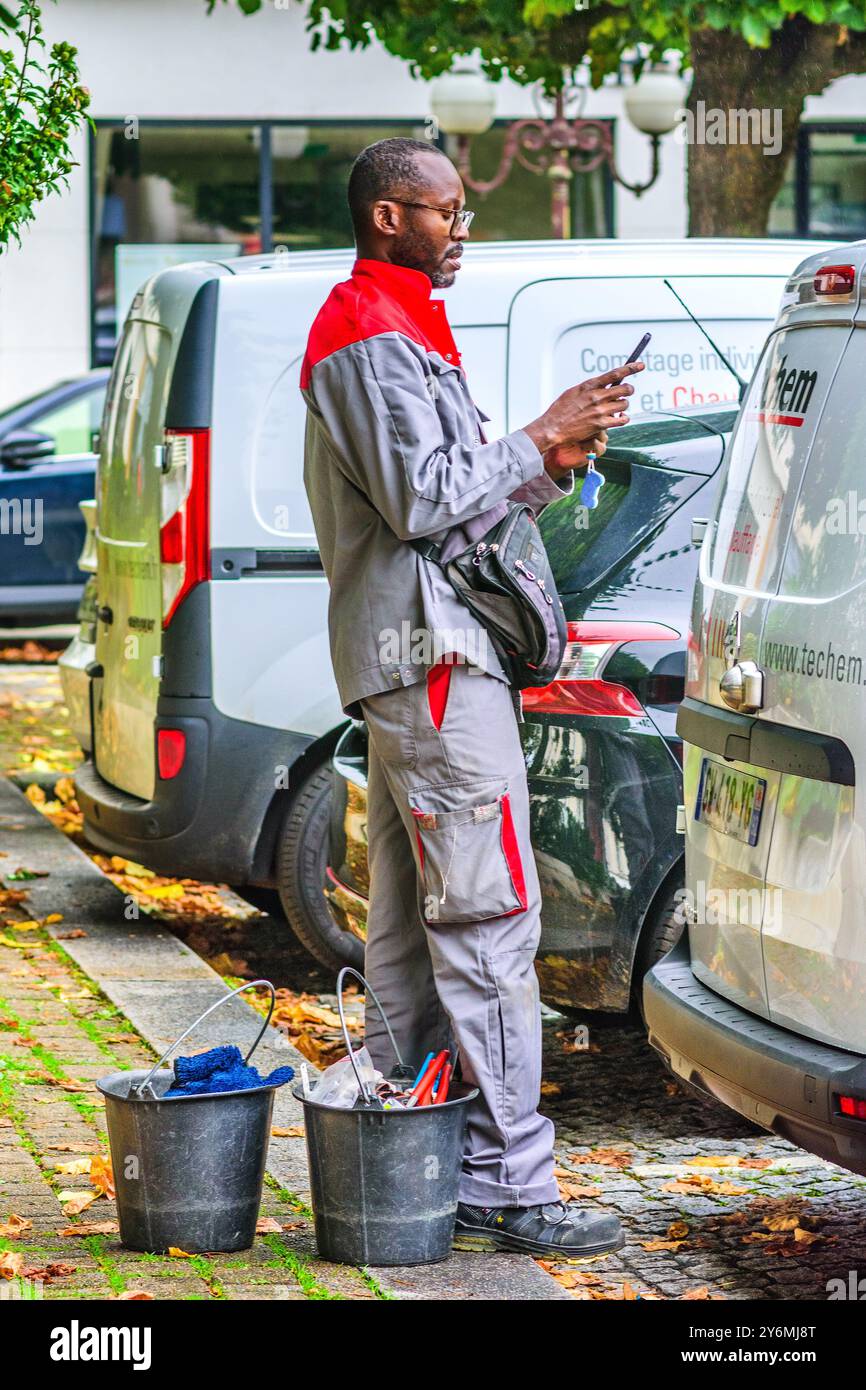Schwarzer französischer afrikanischer Mann, Servicetechniker, Handy überprüfen - Tours, Indre-et-Loire (37), Frankreich. Stockfoto