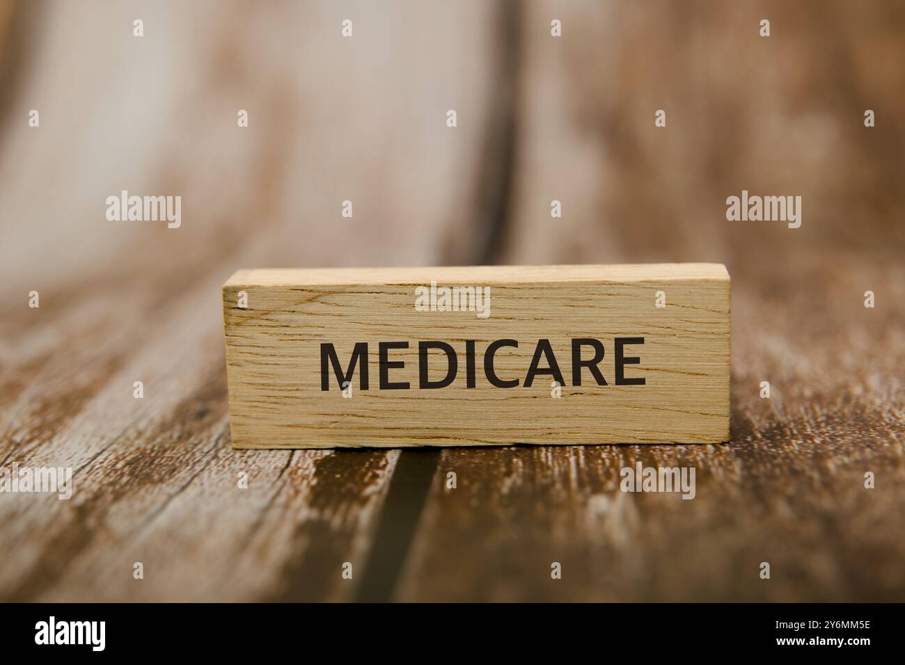 Einfacher Holzblock mit dem Wort „MEDICARE“ auf einer rustikalen Oberfläche. Krankenversicherungs- und Seniorenkonzept. Stockfoto