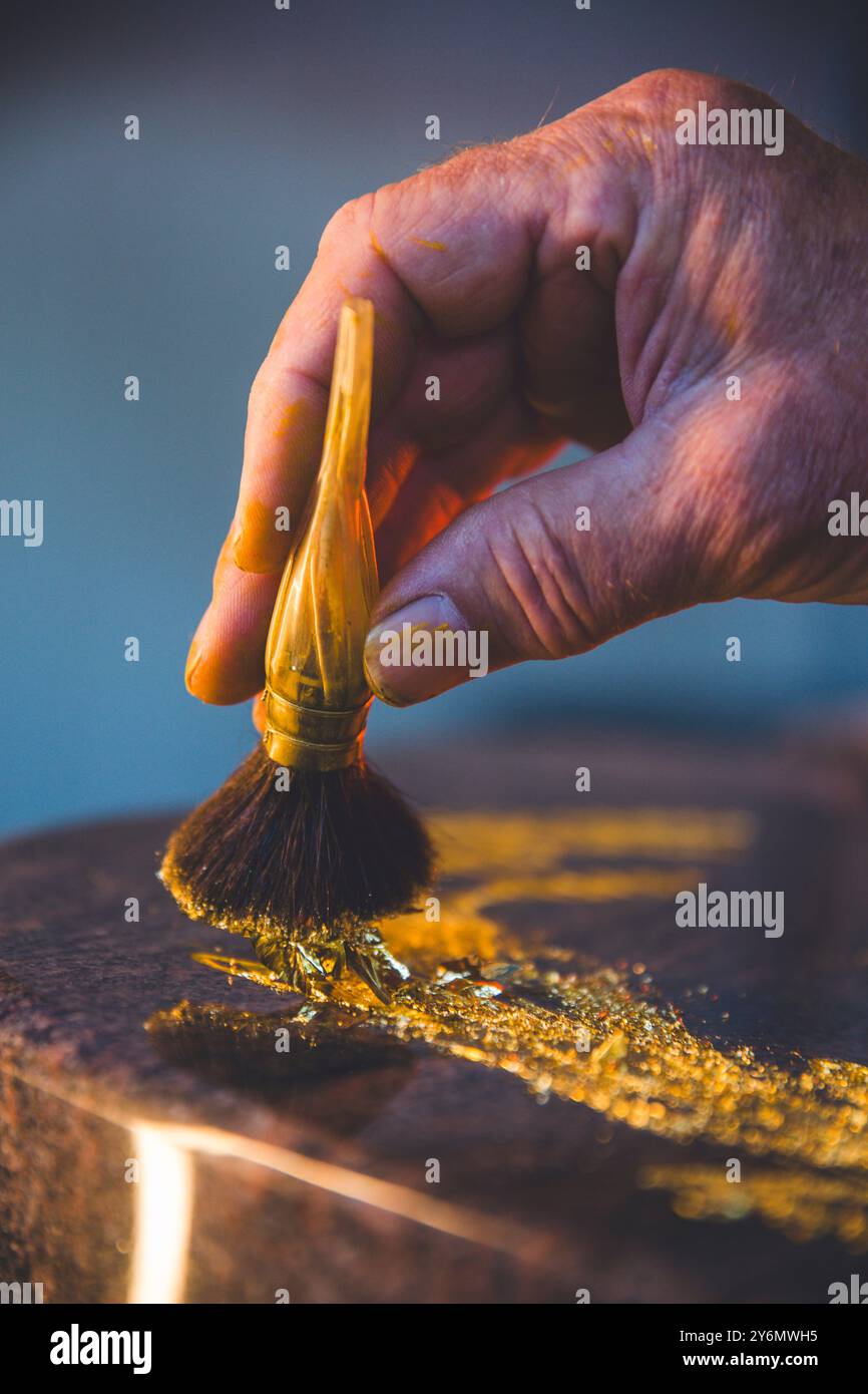 Blattgold mit einem Pinsel auf einen Grabstein auftragen Stockfoto
