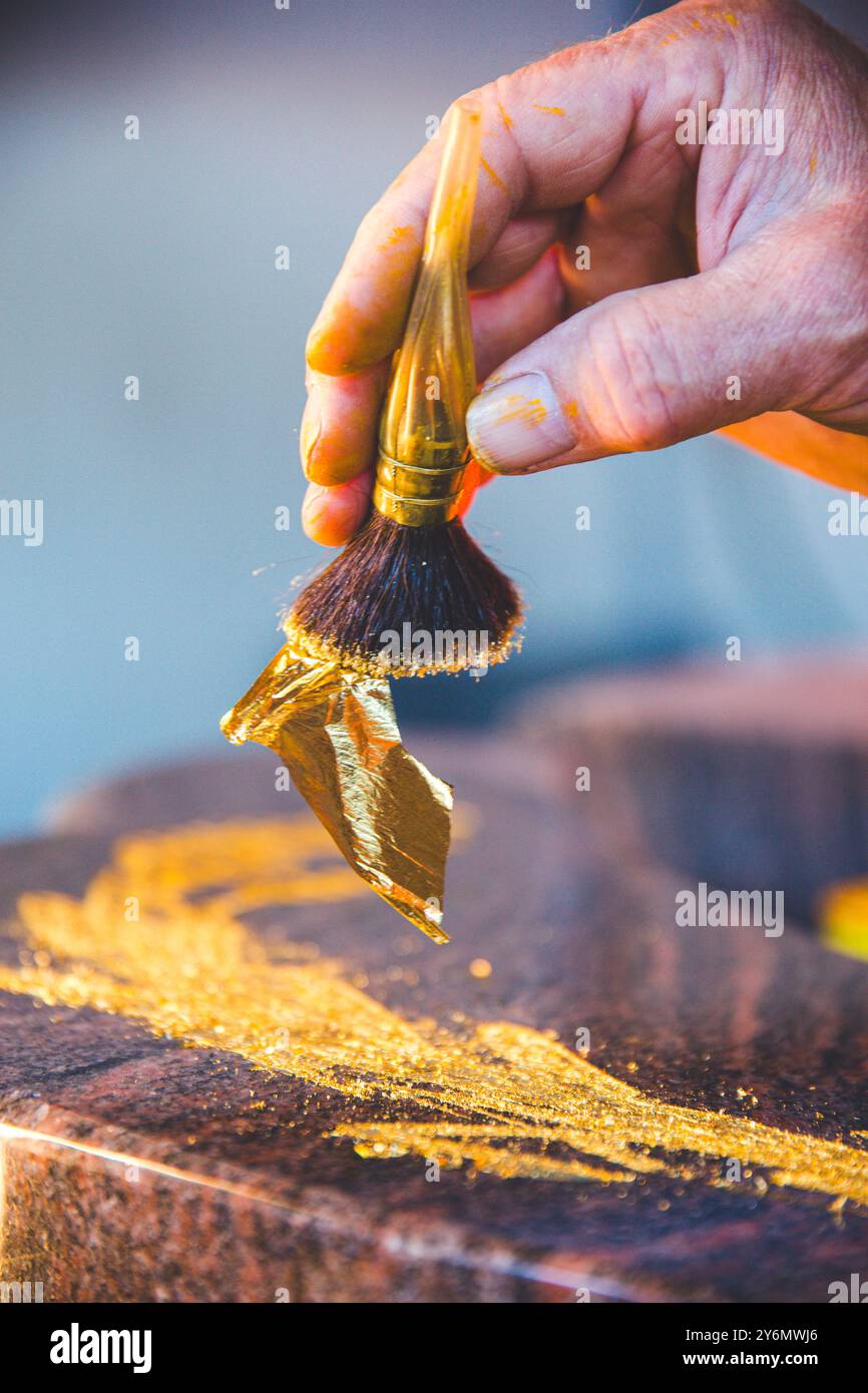Blattgold mit einem Pinsel auf einen Grabstein auftragen Stockfoto