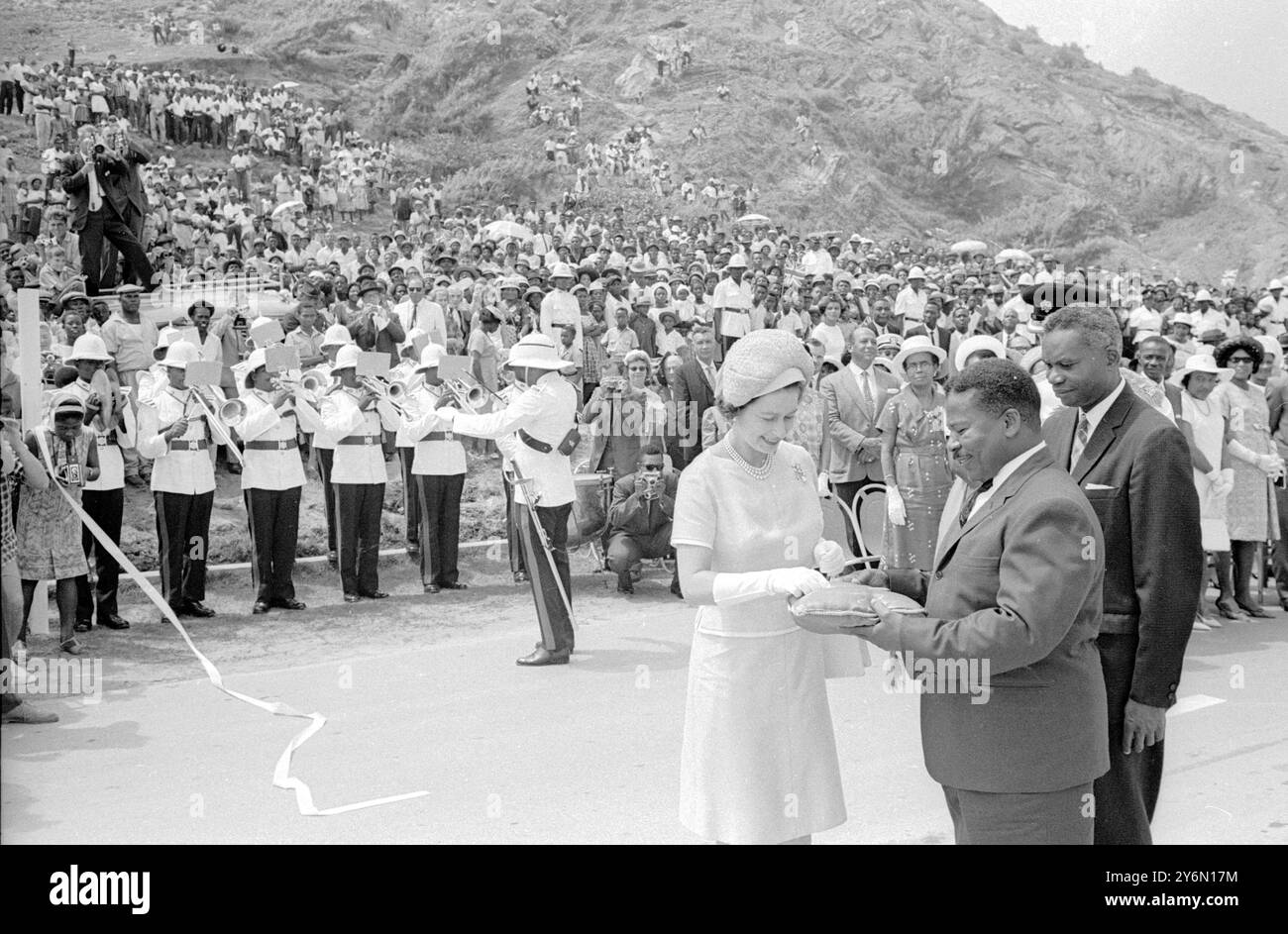 Barbados : die britische Königin Elizabeth II. Schneidet das Band ab, um die New kostspielige East Coast Road an der malerischen Küste der Gemeinde St. Andrew zu eröffnen. Auf der rechten Seite befinden sich Herr Alwyn Wason, Direktor für Autobahnen und Verkehr in Barbados, und Herr Neville Boxill, Minister für Kommunikation. Die Königin und Prinz Philip Duke of Edinburgh waren auf einem zweitägigen Besuch der Insel im Rahmen ihrer aktuellen 5-wöchigen Tour durch die Karibik commonwealth Territorien. 17. Februar 1966 Stockfoto