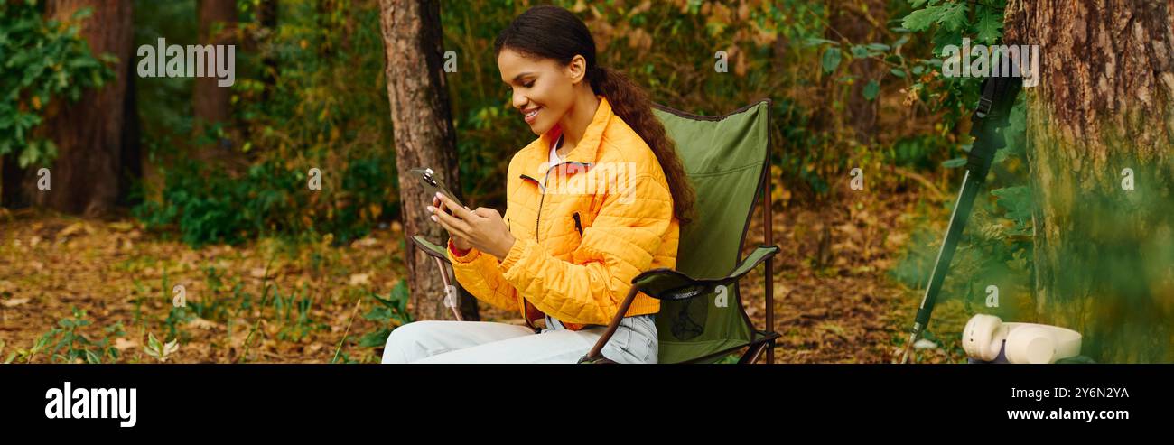 Eine junge Frau in einer orangefarbenen Jacke lächelt, während sie sich mit der Natur verbindet, während sie durch bunte Herbstbäume wandert. Stockfoto