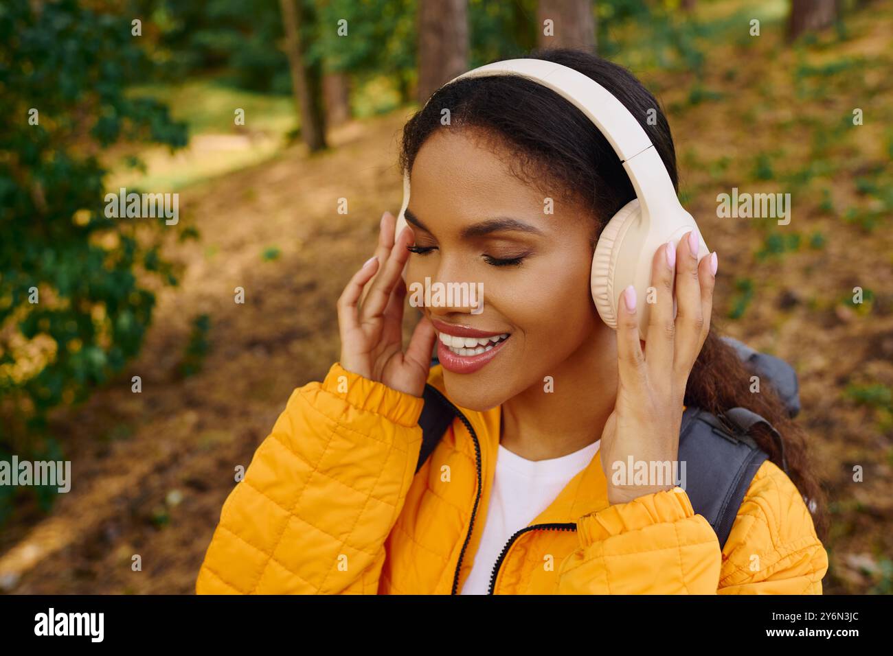 Eine junge afroamerikanische Frau genießt ihre Wanderung durch das lebhafte Herbstlaub, eingebettet in die Ruhe der Natur. Stockfoto