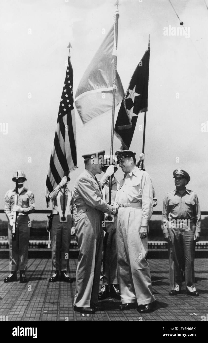 MacArthur unter UN-Flagge. General J Lawton Collins (L) Stabschef der United States Army, der dem General der Armee Douglas MacArthur, dem Oberbefehlshaber der Streitkräfte der Vereinten Nationen, der sich der nordkoreanischen Invasion in Südkorea widersetzt, die Hand schüttelte, als er ihm in Tokio eine Flagge der Vereinten Nationen schenkte. Die Präsentation fand auf dem Dach des Dai Ichi-Gebäudes statt, dem Hauptquartier von General MacArthur. Die UN-Flagge ist im Hintergrund zu sehen, flankiert von Amerikas Sternen und Streifen und General MacArthurs fünf-Sterne-Flagge. 1950 Stockfoto