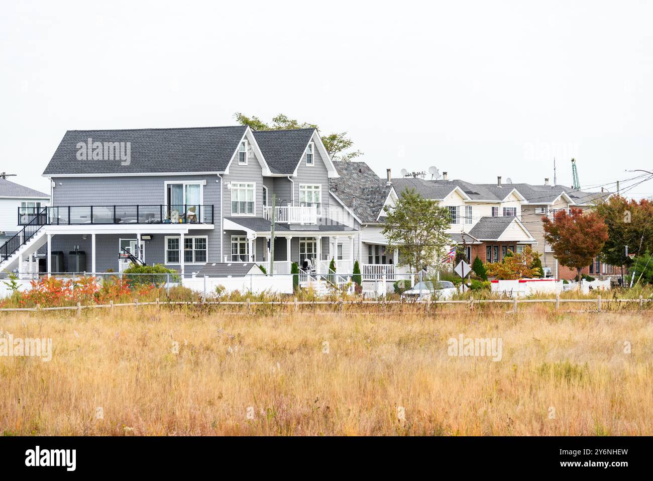 Reihe neuer Einfamilienhäuser in einer Wohnanlage, die an einem bewölkten Herbsttag von einem Park umgeben ist Stockfoto