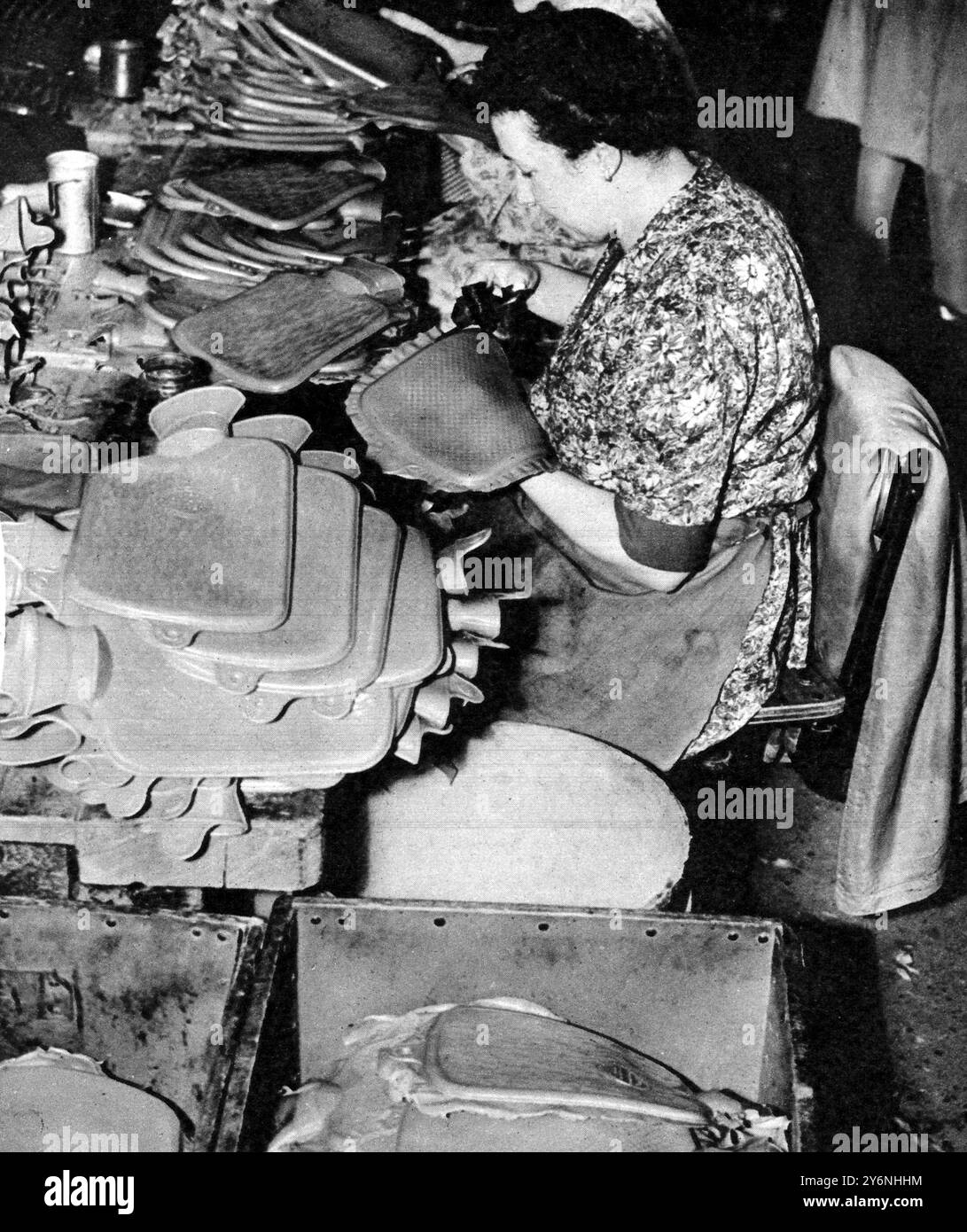 Die Rückgabe der Warmwasserflasche: Die Freisetzung von Gummi, um einen alten und treuen Freund zurückzuholen. Schneiden Sie den Blitz oder Altgummi um den Rand der Umhüllung der Heißwasserflasche ab. Ein Vorgang, der von Hand ausgeführt wird, wenn das Produkt sich dem Ende nähert. 1946 Stockfoto